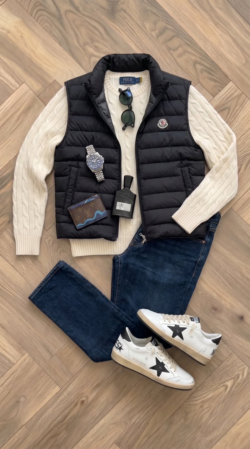 Flat-lay: black Moncler vest, cream sweater and dark jeans with Rolex GMT